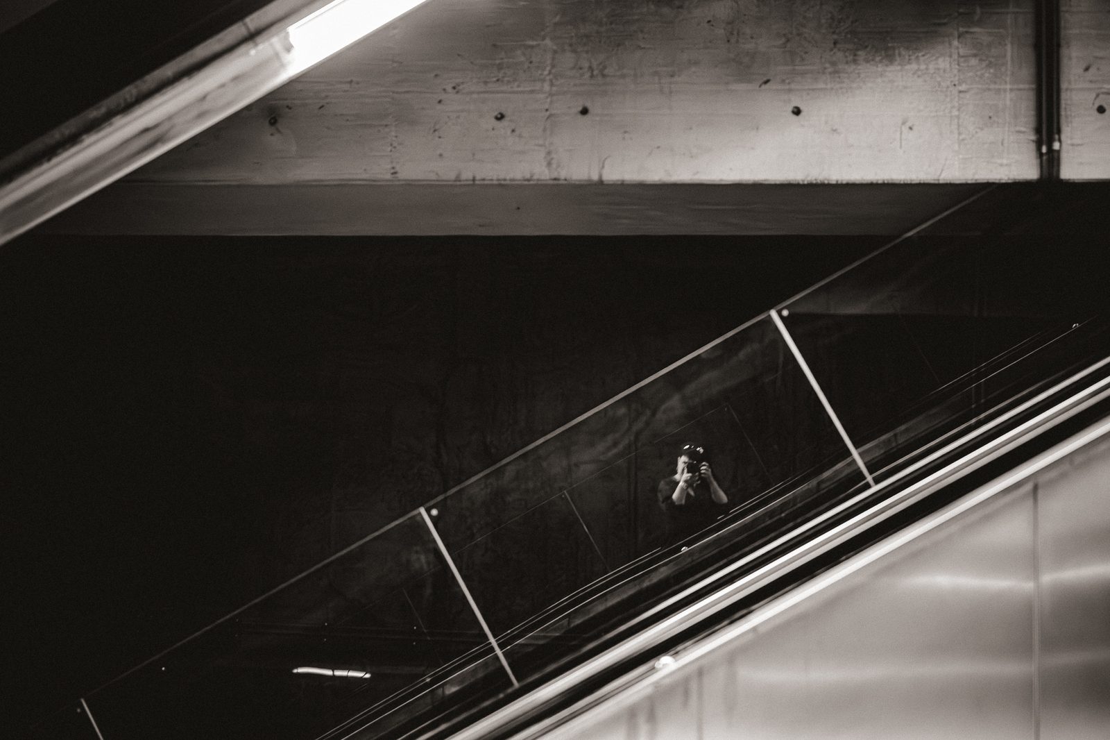 Fotograf mit Kamera, Rolltreppe (Spiegelung)