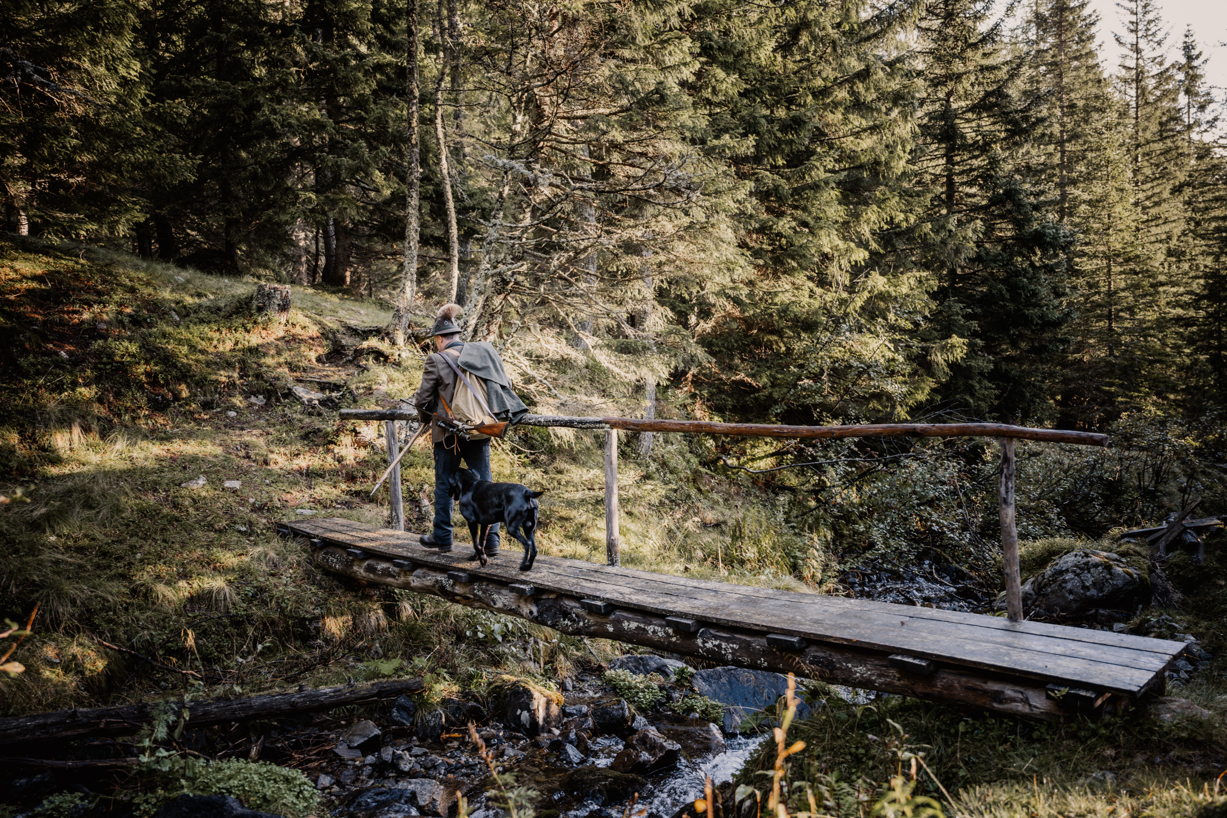 Jäger mit Hund auf dem Holzsteg im Wald – Südtiroler Jagdverband, nominiert „Rund um die Jagd“